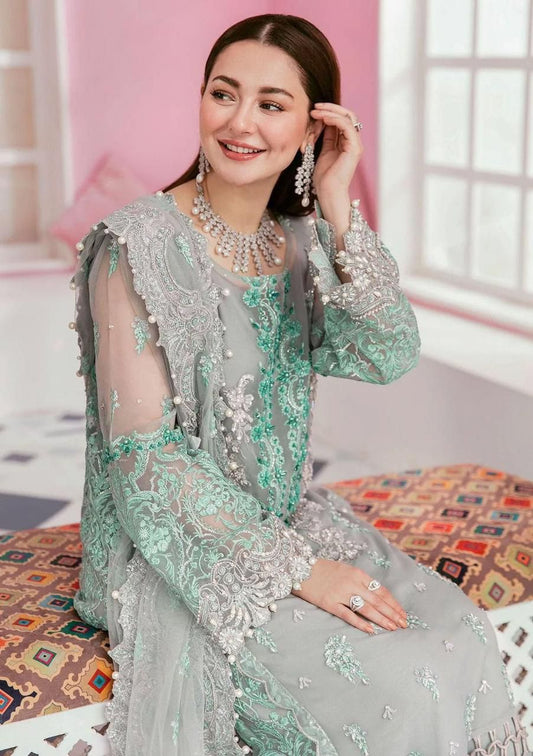 Close-up of intricate silver zari and mint green floral embroidery on a grey formal dress.